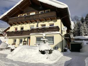 a house covered in snow in front of it at Pension Haus Maria in Ramsau am Dachstein
