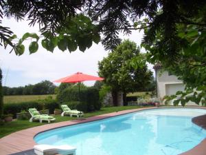 - une piscine avec 2 chaises et un parasol dans l'établissement Le Clos de Saint Amour, à Montauban