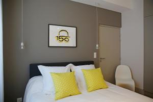 um quarto com uma cama com almofadas amarelas e brancas em Appartements Numeroa em Albi