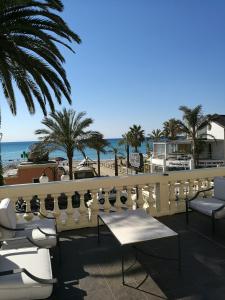 a balcony with chairs and tables and the beach at Hotel De La Plage in Pietra Ligure