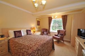 a bedroom with a bed and two chairs and a television at Marton Grange Country House in Bridlington