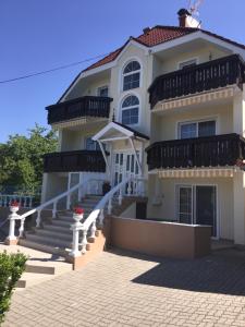 a large white house with a staircase in front at Hibiskus Appartementhaus in Cserszegtomaj