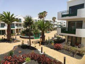 an apartment complex with palm trees and buildings at Apartamento Tahiche in Costa Teguise