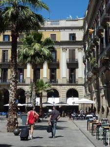 a man and a woman walking down a street with luggage at Roma Reial in Barcelona