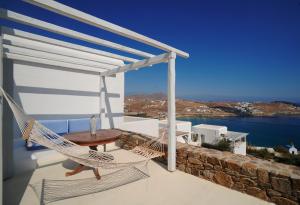 カロ・リヴァディにあるBeachfront Villa Amazing Views Mykonosのポーチ(ハンモック、テーブル、椅子付)