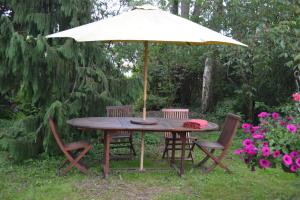 einen Holztisch mit Stühlen und einem Sonnenschirm in der Unterkunft La Licorne in Lamarche-sur-Saône + 8 Fotos