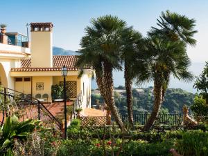 a house with palm trees in a garden at Hotel Sirius in Taormina