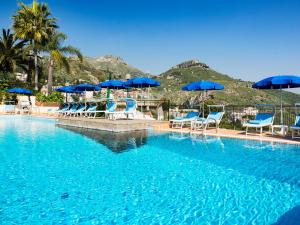 a swimming pool with blue chairs and umbrellas at Hotel Sirius in Taormina