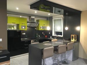 una cocina con armarios negros y verdes y una isla de cocina en Appartement des trois frontières, en Apach