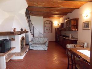 a living room with a fireplace and a kitchen at Casale Le Querciole in Castiglione dʼOrcia