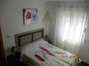 a bedroom with a bed with a white curtain and a window at Apartamento a 100m de la playa in Torrevieja