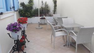 a patio with white chairs and tables and flowers at Villa Roussa in Fira