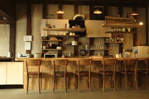 una cucina con bar con tavoli e sedie in legno di Hostel&Bar CAMOSIBA a Yokote