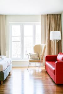 a bedroom with a red couch and a chair at Domizil Gols, Boutique - Hotel in Gols