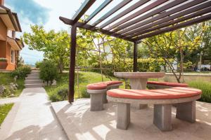 a picnic table and benches under a pergola at Apartment Kampel in Koper