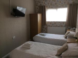 格蘭瑟姆的住宿－The Avenue Hotel，酒店客房设有两张床和一台墙上的电视。