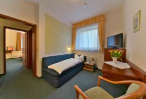 ein Hotelzimmer mit einem blauen Sofa und einem TV in der Unterkunft Hotel & Restaurant Krone in Kestert