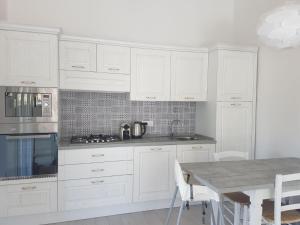 a white kitchen with white cabinets and a table at Ca' Viscomi in San Teodoro