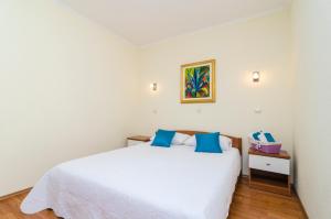 a bedroom with a white bed with blue pillows at Apartments Dora Mljet in Kozarica