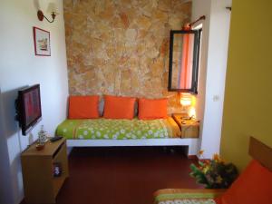 a bedroom with a bed with orange pillows and a stone wall at Apartamento em Pedras del Rei in Moncarapacho