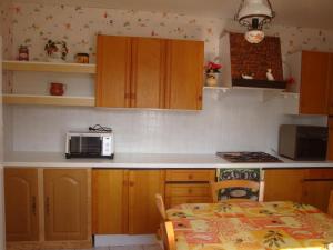 cocina con armarios de madera, mesa y microondas en La Tuilerie, en Noyers-sur-Cher 7 fotos más