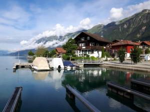 einen See mit einem Haus und einer Anlegestelle mit Zelten in der Unterkunft Romantic Lake & Mountain apartment Pure Swissness in Brienz