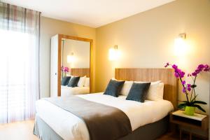 ein Hotelzimmer mit einem großen Bett und einem Spiegel in der Unterkunft Lagrange Aparthotel Toulouse Saint-Michel in Toulouse
