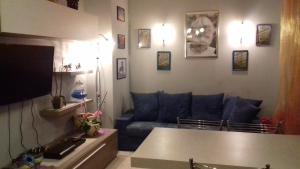 sala de estar con sofá azul y TV en Appartamento con giardino privato en Santo Stefano al Mare