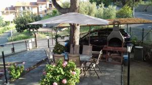 Appartamento con giardino privato في سانتو ستيفانو أل ماري: طاولة وكراسي تحت مظلة بجانب سيارة