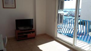 a living room with a flat screen tv and a balcony at Vista Mar Apartment in L'Ampolla