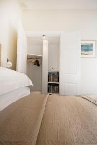 a white bedroom with a large bed and a closet at The Grapevine Studio in Cambridge