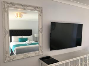 a mirror in a room with a bed and a tv at Araluen Motor Lodge in Batemans Bay