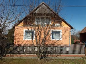 uma casa cor-de-rosa com uma vedação à frente. em Rita vendégház em Villány