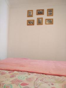 リスボンにある36for2のピンクベッド1台付きのベッドルーム1室、壁に4枚の写真が飾られています。