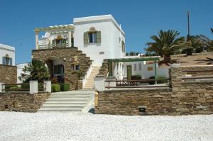 a white house with a stone wall at Tinos View Apartments in Tinos Town