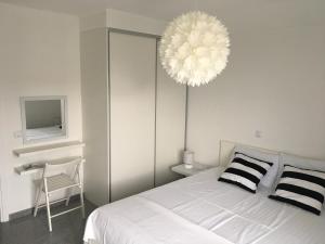 1 dormitorio con cama blanca y lámpara de araña en Casa Vito, en Nin