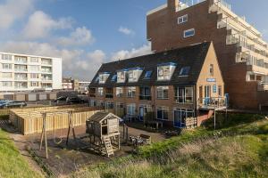 un edificio de apartamentos con un gran edificio delante de él en Perfect Stay Holiday, Sea View en Egmond aan Zee