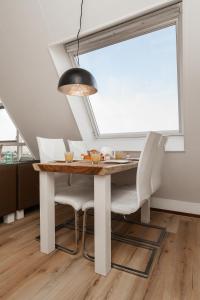 einen Esstisch mit weißen Stühlen und einer schwarzen Lampe in der Unterkunft Perfect Stay Holiday, Sea View in Egmond aan Zee