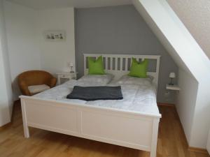 a bedroom with a white bed with green pillows at Ferienwohnung Marschblick in Mildstedt