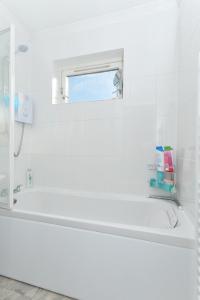 ein weißes Bad mit einer Badewanne und einem Fenster in der Unterkunft Edinburgh Seaside Apartment in Edinburgh