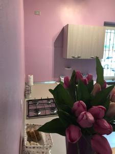 a vase filled with pink flowers in a kitchen at Casa Mirabello in Peveragno