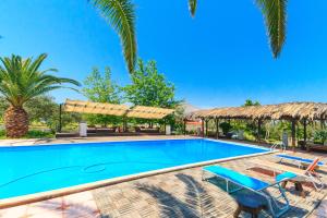a swimming pool with palm trees and a resort at Kissos Apartments in Vourvourou