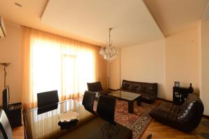 a living room with leather furniture and a chandelier at Meri's Apartment in Batumi