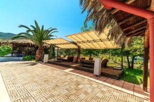 a patio with umbrellas and couches and palm trees at Kissos Apartments in Vourvourou