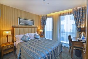 イスタンブールにあるAdelmar Hotel Istanbul Sisliのベッド、デスク、窓が備わるホテルルームです。