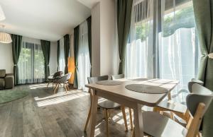 uma sala de jantar com mesa, cadeiras e janelas em Vila Cotroceni Boutique Apartments em Bucareste
