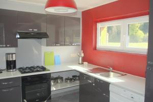 eine Küche mit roten Wänden, einer Spüle und einem Herd in der Unterkunft l'oiseau d'eau in Bouillon