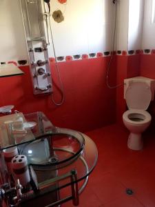 a red bathroom with a toilet and a glass sink at Guest House Pautalya in Kyustendil