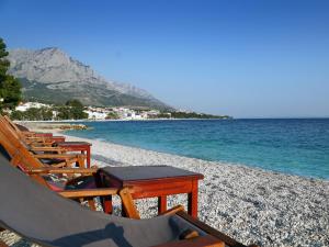 un grupo de sillas y mesas en una playa en Apartments Feral, en Baška Voda