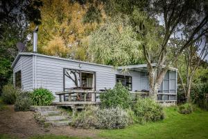 a gray house with a porch and a tree at Absolute Lakefront Location in Taupo